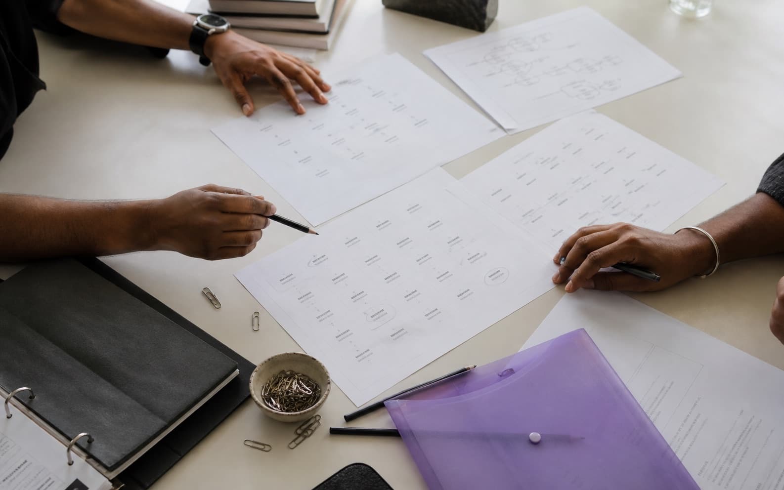 Designers reviewing printed brand-name research at a studio table